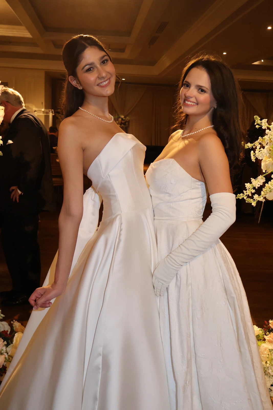 Two guests in white gowns at a formal event