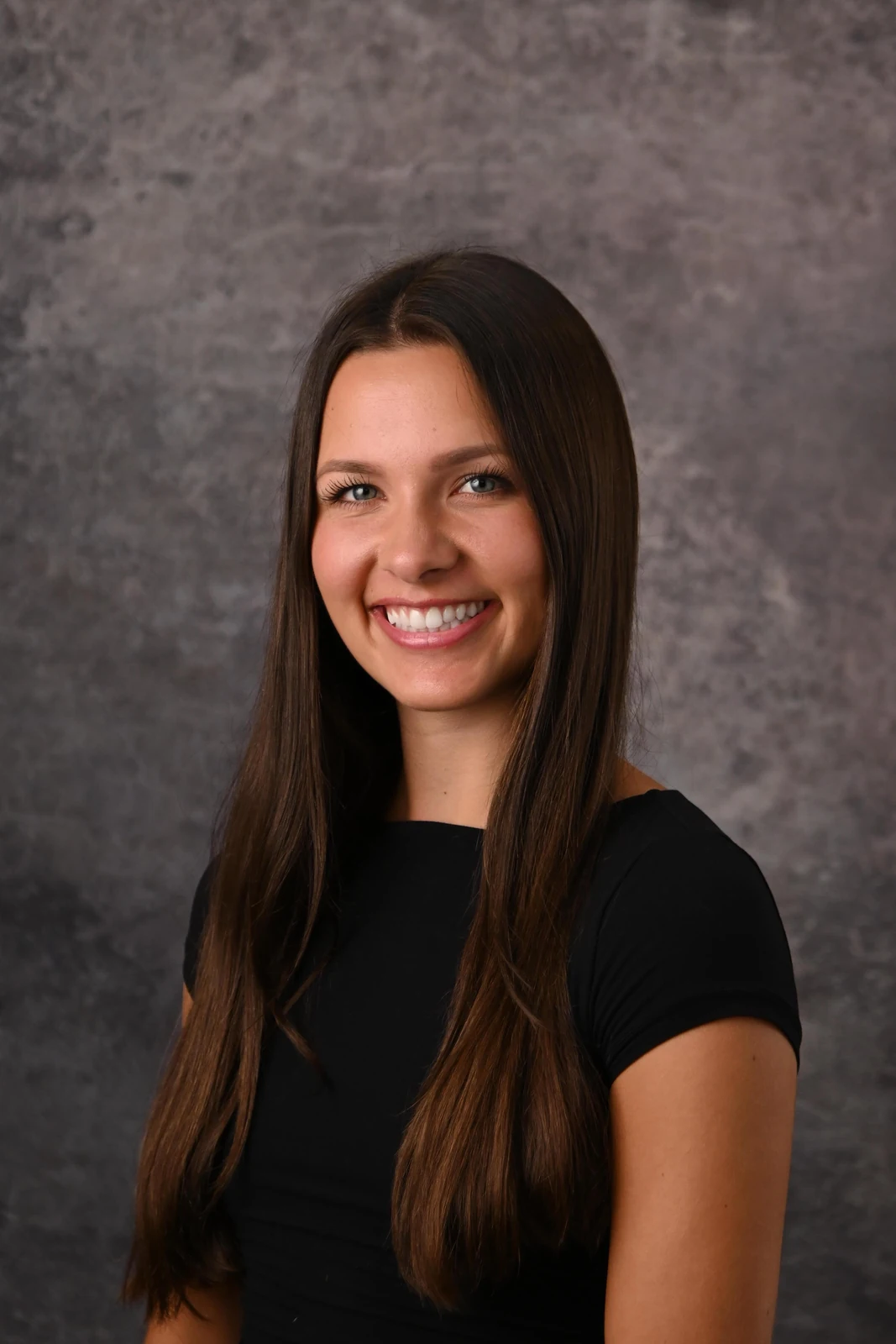 Professional studio headshot against a neutral gray background